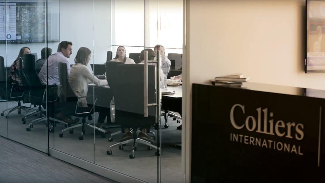 Colliers International employees meet in a conference room with glass walls and doors